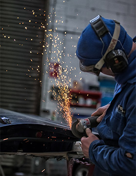 Car bodywork specialist grinding out damage cause by accident
