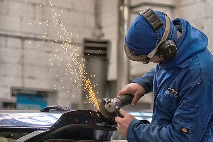 Car body specialist grinding out damage from audi a3 door