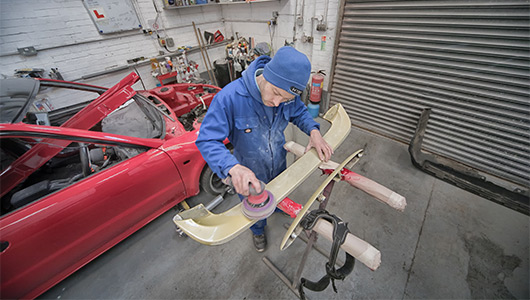 Body work specialist sanding spoiler ready for respray